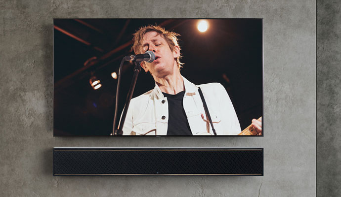 A large flat screen TV with high-end audio system mounted on wall