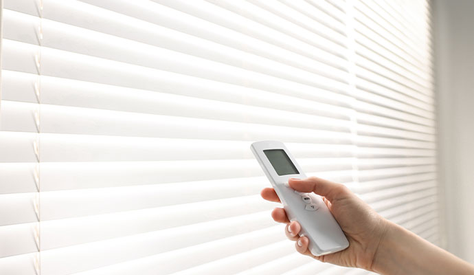 A person using remote to control motorized window cover