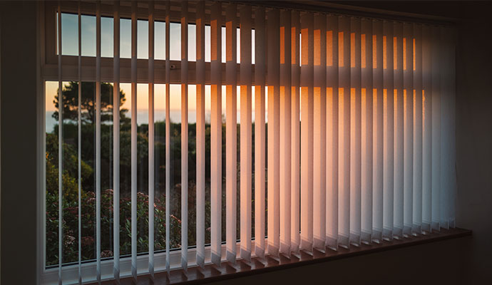 A residential window fitted with vertical blinds