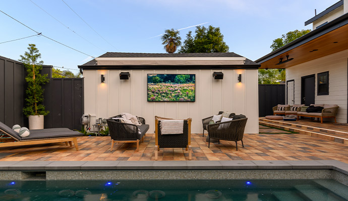 Outdoor patio with pool and wall mounted outdoor tv