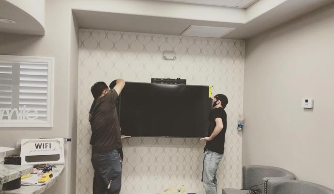 Two experts mounting a flat-screen television on a wall