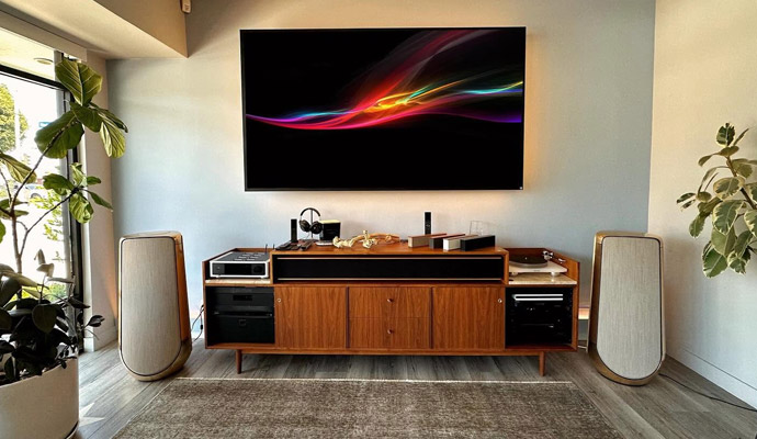 High-end home audio and video system with wall-mounted display and floorstanding speakers.