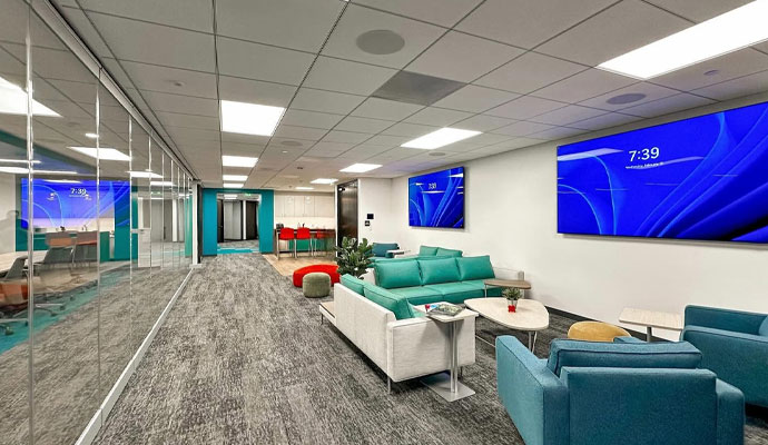 Modern office lounge with teal seating and wall mounted screens