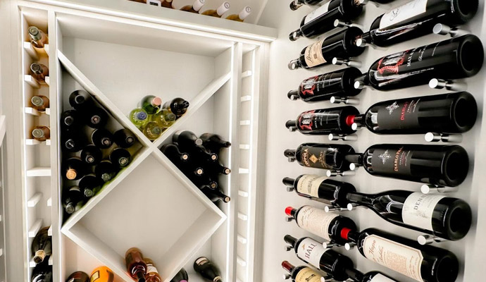 Custom luxury wine room featuring illuminated display shelving and modern metal wine racks.