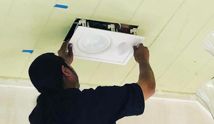An expert installing a square light fixture
