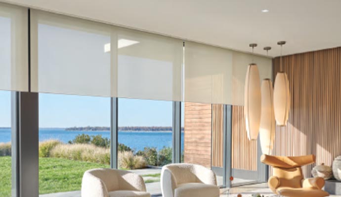 Sunny room with a view of the ocean, featuring white armchairs, modern lights, and white window shades