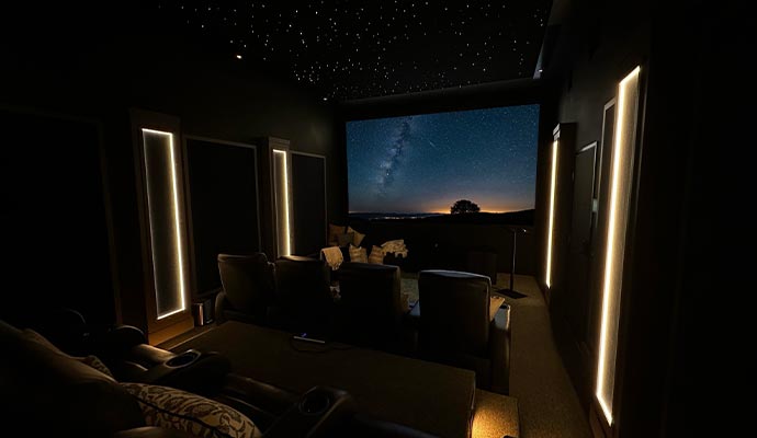 Modern luxury home theater with large screen Luxury home theater featuring reclining seats and a large screen displaying a starry night sky