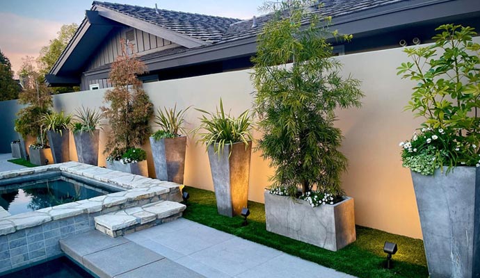 Outdoor landscape lighting in modern backyard Modern backyard with stone pool and warm outdoor lighting