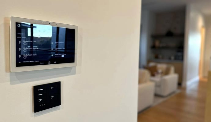 Wall-mounted smart home control panel with media room settings Wall-mounted smart home control panel displaying media room settings with a secondary switch panel below in a modern living space