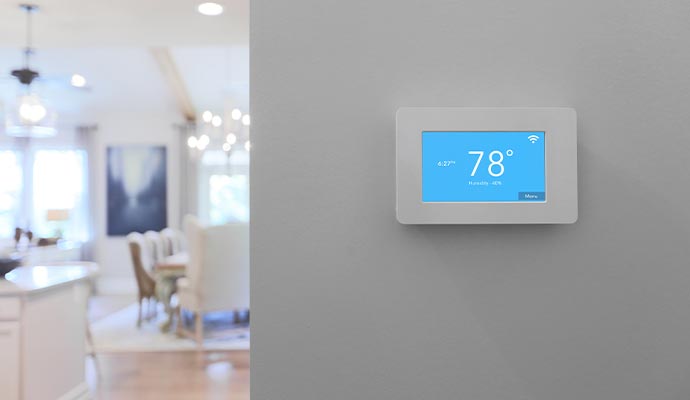 Smart home thermostat with temperature and humidity display Smart home thermostat mounted on wall showing temperature and humidity in a modern home