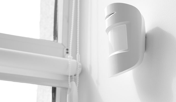 Wireless home security motion sensor mounted on wall