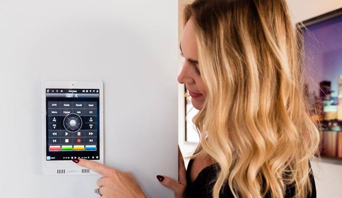 Woman using wall-mounted smart home control panel Woman using a wall-mounted smart home control panel with various media and automation options displayed on the screen