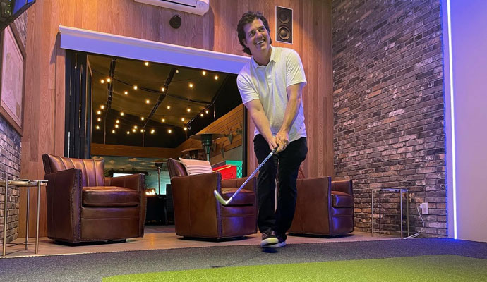 Homeowner practicing golf swing in custom game room