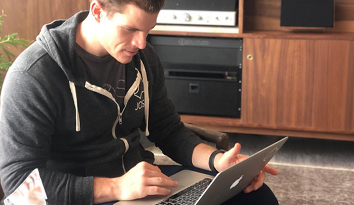 Man using a laptop in front of a home audio cabinet.