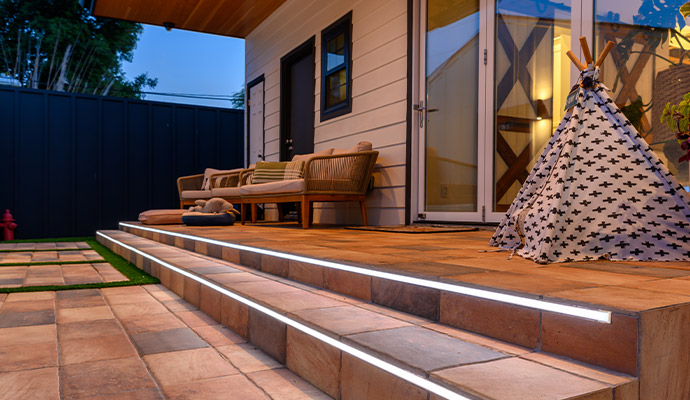 Outdoor patio steps with illuminated LED strip lighting and architectural exterior lights.