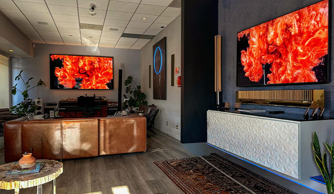 Luxury smart home showroom living space featuring leather sofa and dual digital art displays.