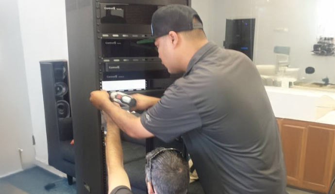 Technicians installing Control4 equipment in a network rack.
