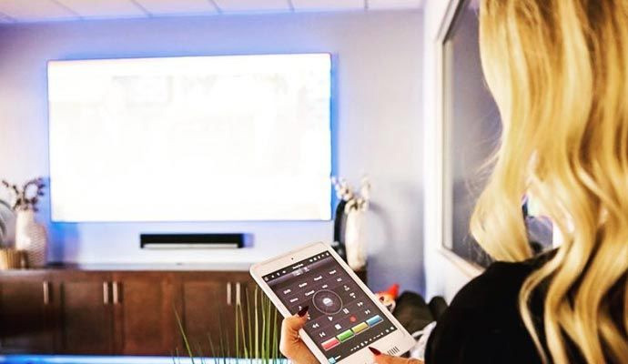Woman using a tablet to control a home theater screen.